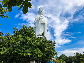 Low angle view of statue against trees against sky