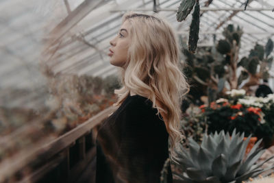 Side view of young woman standing against plants