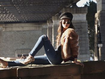 Young woman sitting on built structure