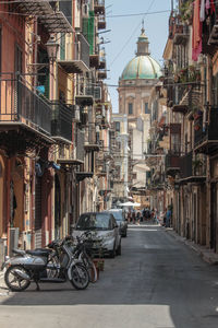 Italian scene of a street in palermo in sicily during the summer, with a motorbike and carts