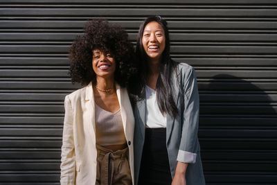 Multiracial friends standing in front of shutter on sunny day