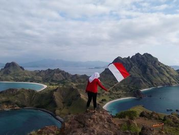 Man standing on rock by mountains against sky