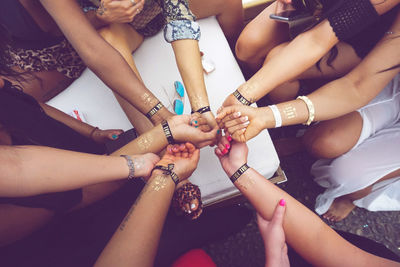 High angle view of female friends showing text on hands during bachelorette party