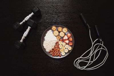 High angle view of healthy food with dumbbells and jump rope on table