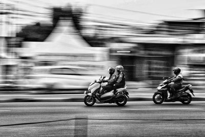 Rear view of man riding motor scooter on street