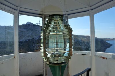 Reflection of mountain in sea against sky seen through window