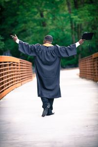 Rear view of man with arms outstretched standing outdoors