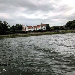 Buildings by river against sky