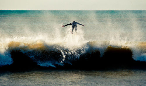 Man surfing in sea against sky