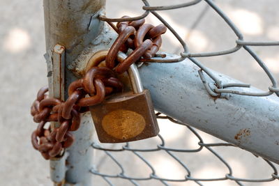 Close-up of rusty chain hanging on metal fence