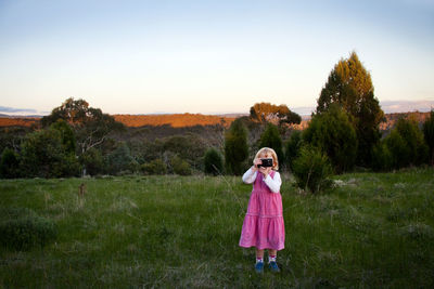 Girl taking photographs on grassy field