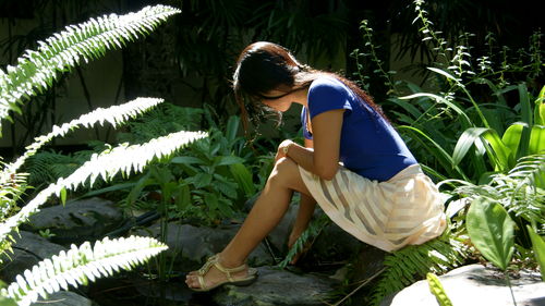 Side view of young woman standing amidst plants