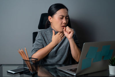 Young woman using mobile phone while sitting on table