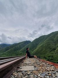 Rear view of man on railroad track against sky