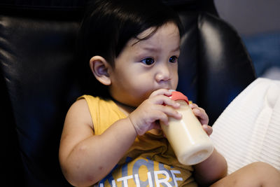 Close-up of young woman drinking milk at home