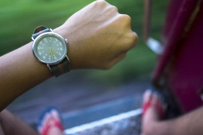 Close-up of hand holding clock against blurred background