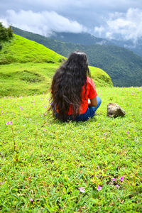 Rear view of woman sitting on grassy field