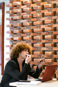 Portrait of woman using mobile phone while sitting in cafe