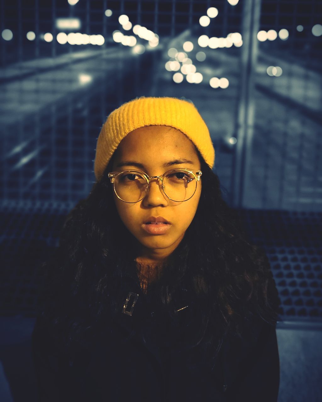 one person, glasses, eyeglasses, front view, real people, leisure activity, lifestyles, portrait, clothing, illuminated, looking at camera, night, indoors, focus on foreground, young women, waist up, women, hat, young adult, hairstyle, warm clothing, scarf