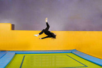 Side view of man jumping against yellow sky