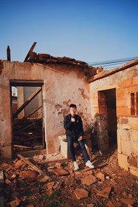 Man standing by abandoned building against sky