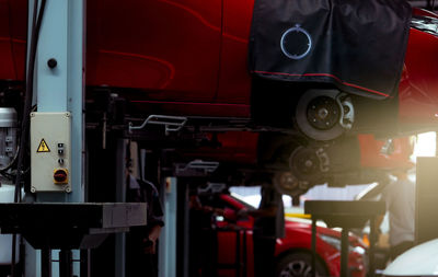 Selective focus on lift in auto repair shop. red suv car lifted in the garage for repair.