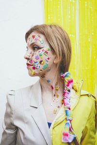 Woman with stickers on face standing in front of two tone wall