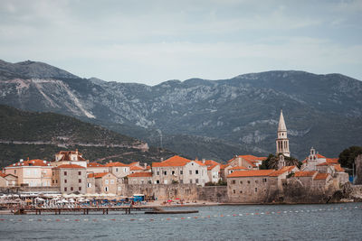 Buildings at waterfront against cloudy sky