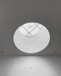 Low angle view of illuminated pendant light against wall