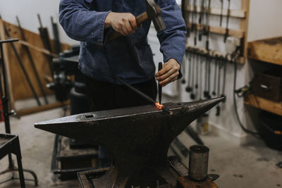 Blacksmith using hammer and anvil in workshop