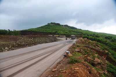 Road leading towards mountain against sky