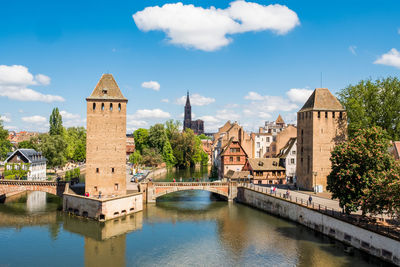 Arch bridge over river by buildings against sky in city