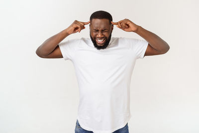 Frustrated young man standing against white background