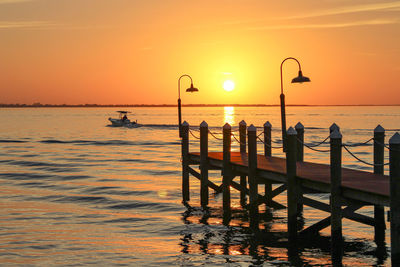 Silhouette jetts on beach against orange sky with boat