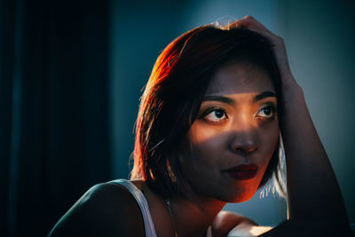 Close-up of thoughtful young woman sitting at home