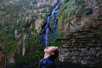 Side view of man looking up rock