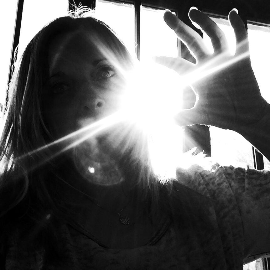 CLOSE-UP PORTRAIT OF YOUNG WOMAN WITH HAND IN SUNLIGHT