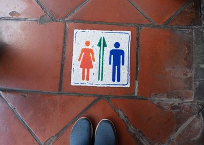 Low section of person standing on road sign