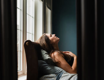 Mirror reflection of woman laying on a bed in a dark bedroom.