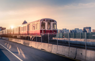 Train in city against sky during sunset