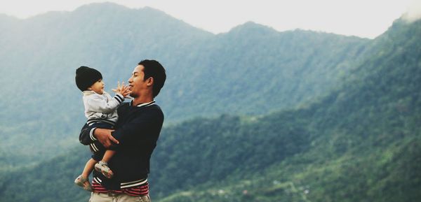 Rear view of mother and daughter on mountain against sky