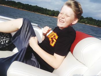 Cheerful boy sitting in boat on lake