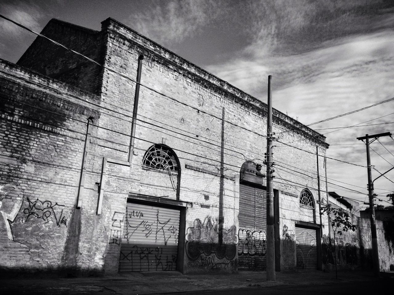 architecture, built structure, building exterior, sky, low angle view, building, graffiti, cloud - sky, window, wall - building feature, day, abandoned, outdoors, no people, city, cloudy, brick wall, wall, text, old