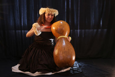 Close-up of woman wearing headdress while dancing against wall