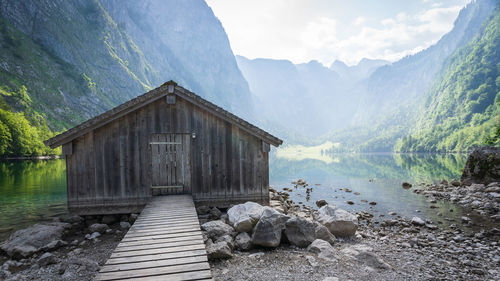 Old wooden boathouse with boardwalk with pristine alpine lake and mountains in background, obersee