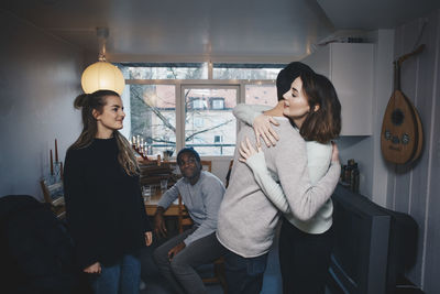 Friends looking at man and woman hugging in college dorm room