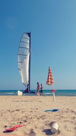 People on beach against clear blue sky