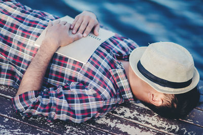 Midsection of man sleeping in hat