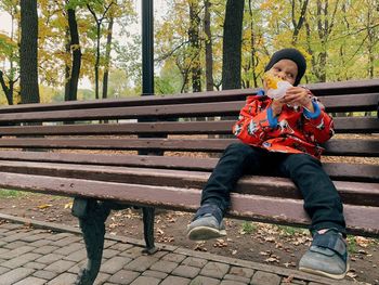 Side view of a child sitting on a park bench