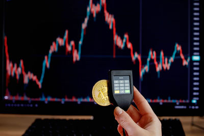 Close-up of hand holding credit card against black background